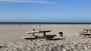 A beach with picnic tables and a trash can.