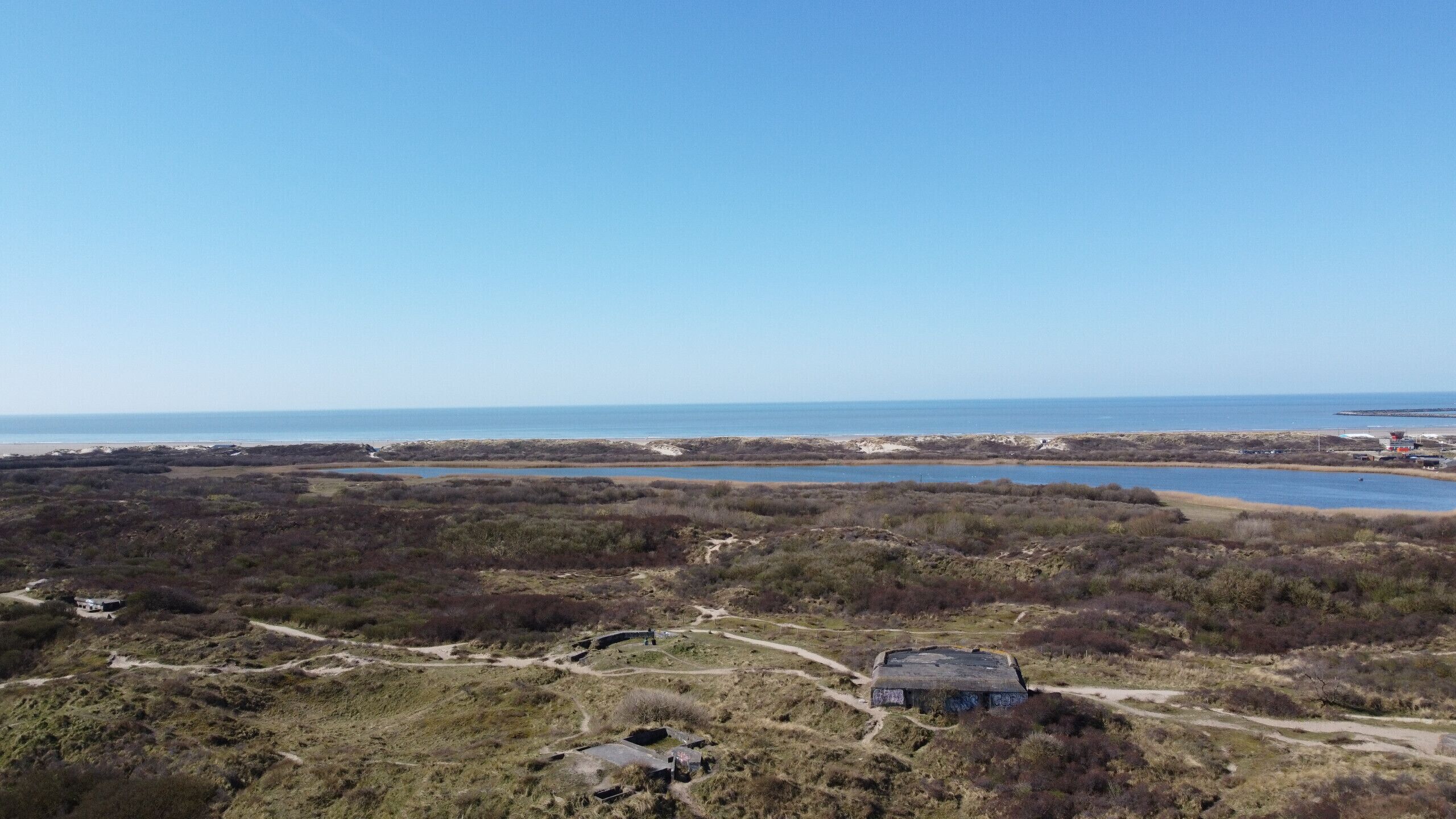 Eine Küstenlandschaft mit einem Gebäude, das von Wegen und Vegetation umgeben ist.