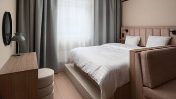 Una habitación de hotel moderna con una cama de madera, una mesita de noche, una lámpara y un ventanal con cortinas.