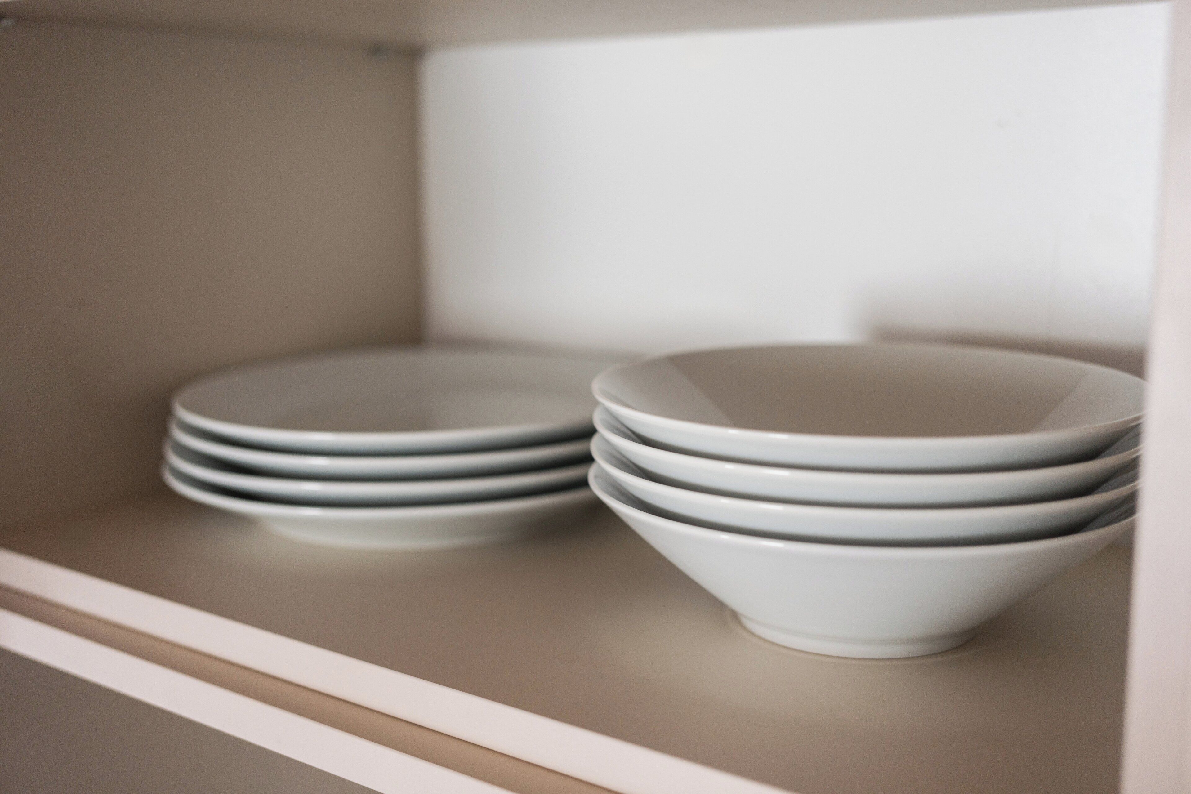 A shelf with stacked white bowls and plates.