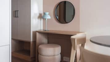 Una habitación moderna con un escritorio de madera, un espejo redondo, un taburete pequeño y una mesa con sillas.