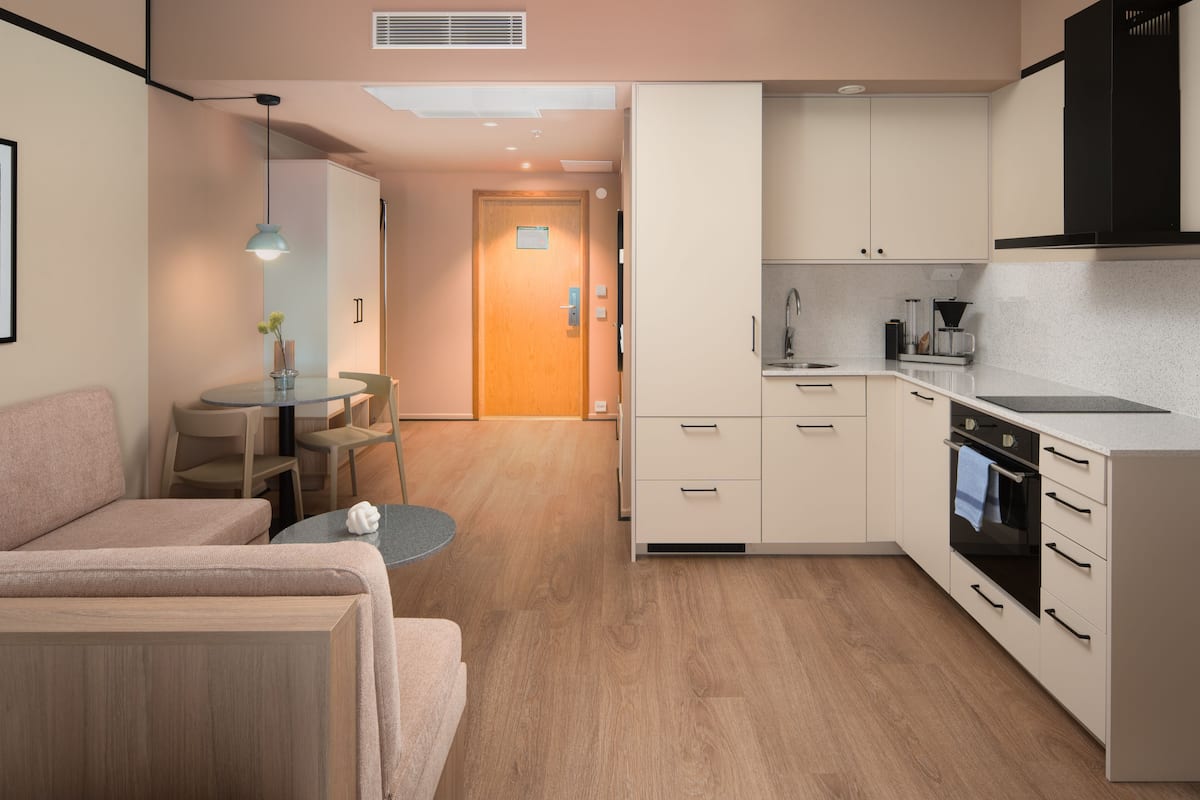 A compact kitchen with a dining area, a sofa, and a small table.