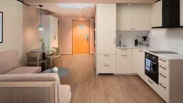 A compact kitchen with a dining area, a sofa, and a small table.