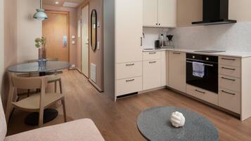 A modern kitchen with a round dining table, chairs, a small island, and a built-in oven.