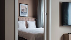 Een hotelkamer met een bed, een lijst aan de muur, een televisietoestel en een deur.