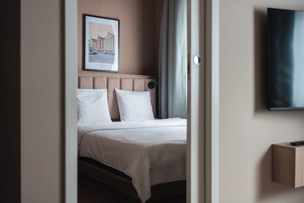 Habitación de hotel con una cama, un cuadro en la pared, un televisor y una puerta.