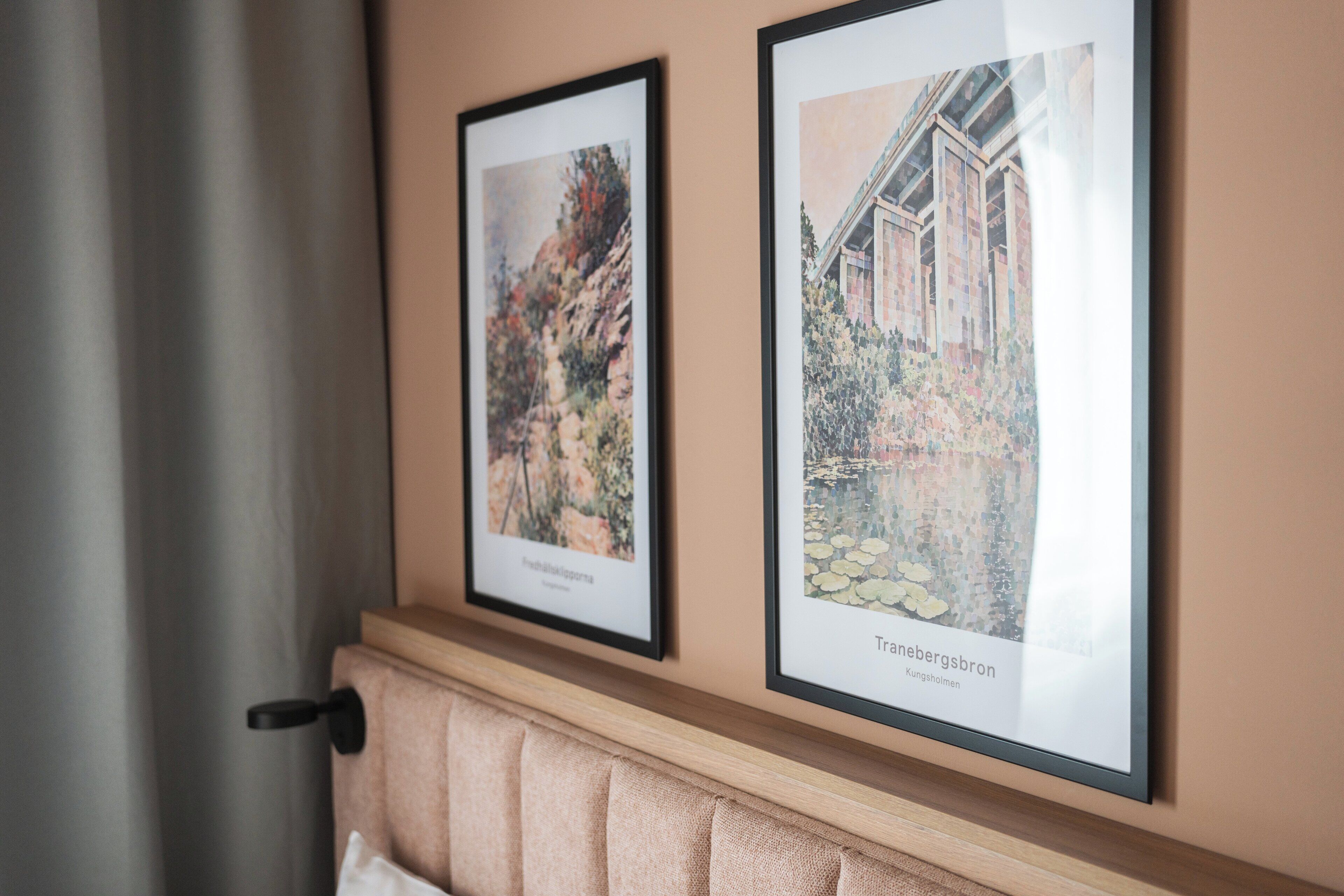 Two framed artworks on a wall above a cushioned bench.