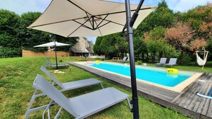 A backyard with a swimming pool, lounge chairs, and a wooden deck. - Cottage for 10 p max / Private swimming pool / Pond / Ideal location / Paris less 1 hour (La Chapelle-Rablais)