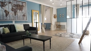 A modern living room with a black sofa, a coffee table, and a world map mural. - Cottage for 10 p max / Private swimming pool / Pond / Ideal location / Paris less 1 hour (La Chapelle-Rablais)