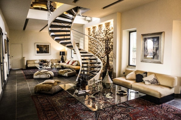 A spacious living room with a spiral staircase, a sofa set, and a coffee table.