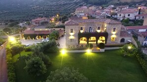 A stone building with a courtyard, surrounded by a well-maintained lawn and trees. - Location Sardinia Borgo Antico XIX (Gesturi)