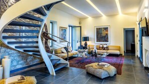 A modern interior with a spiral staircase, a living room with a sofa and coffee table, and a painting on the wall. - Location Sardinia Borgo Antico XIX (Gesturi)