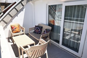 A balcony with a table and two chairs, a sliding glass door, and a staircase. - Livia Residence (Konyaalti)
