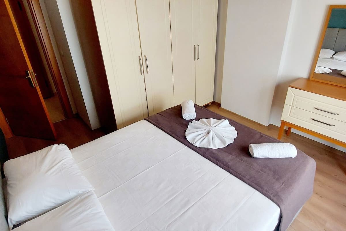 Ein Schlafzimmer mit Bett, Kommode, Spiegel und Kleiderschrank.