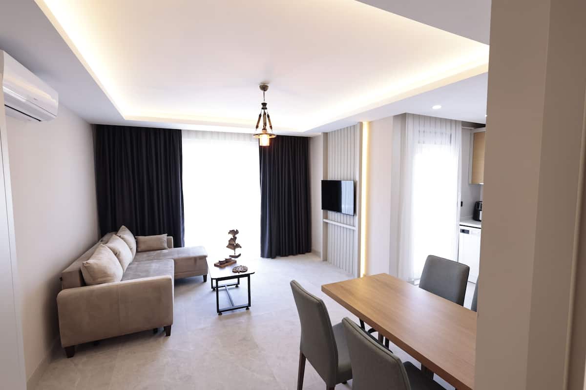 Ein modernes Wohnzimmer mit einer Couch, einem Esstisch und einem Fernseher.