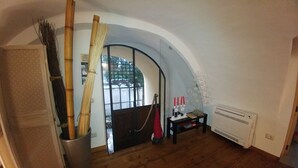 An arched doorway leading to a room with a wooden floor, a radiator, and a small table with candles.