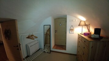 A compact room with a radiator, a mirror, a wooden dresser, and a door leading to another room.