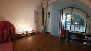 A room with wooden flooring, a red sofa, and a table with decorative lights.