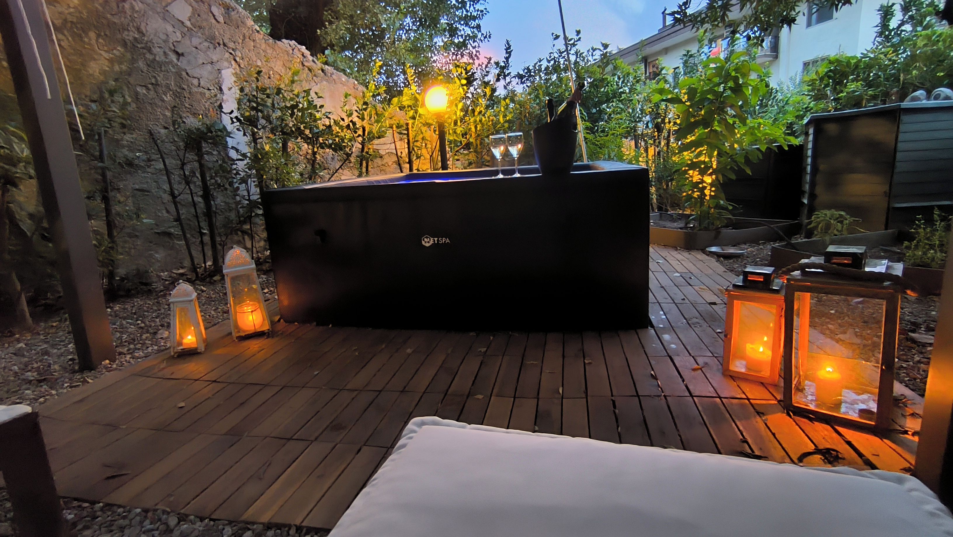 Eine Terrasse im Freien mit Whirlpool, umgeben von Laternen und Pflanzen.