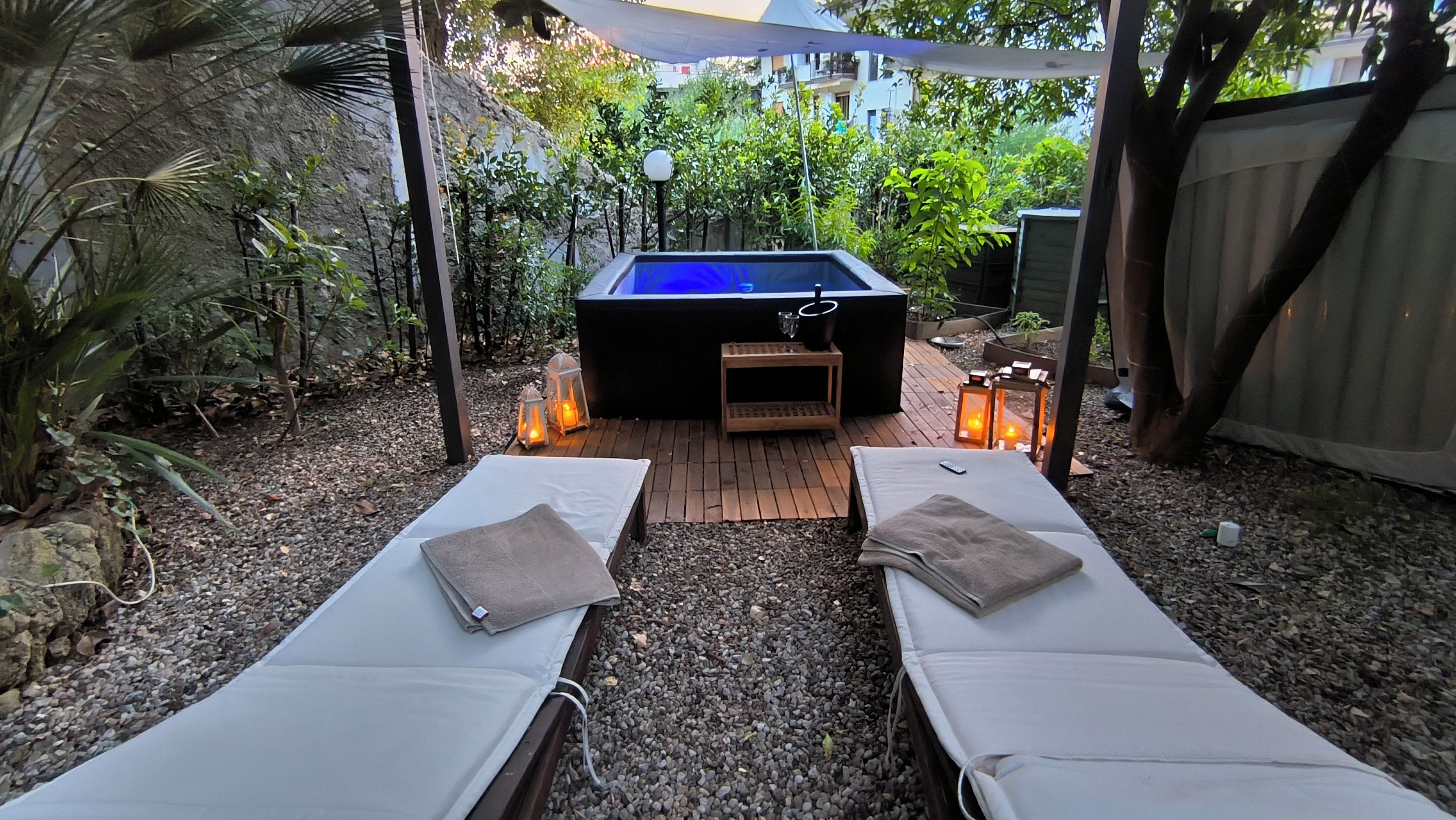 A spa area with two lounge chairs, a hot tub, and lanterns.