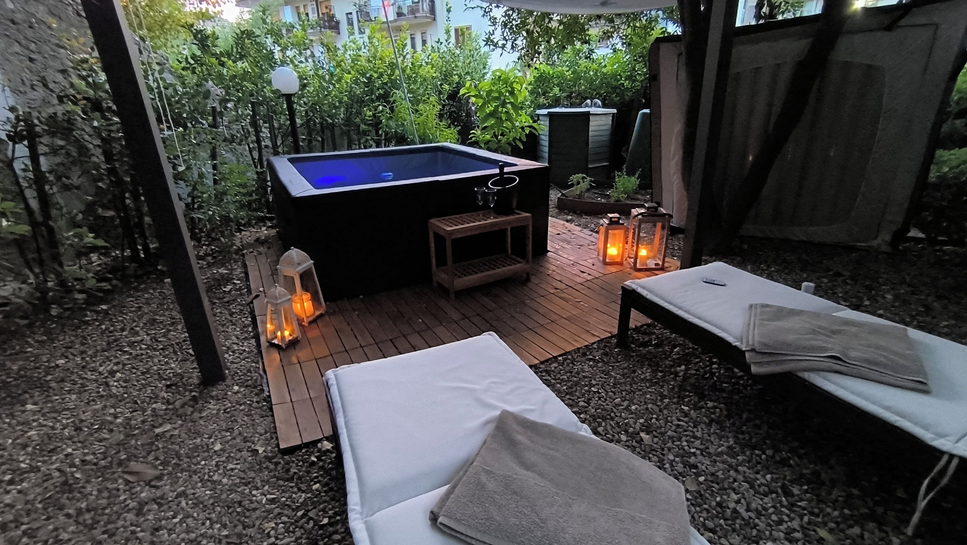A pool table with a wooden deck, two lounge chairs, and two lanterns.