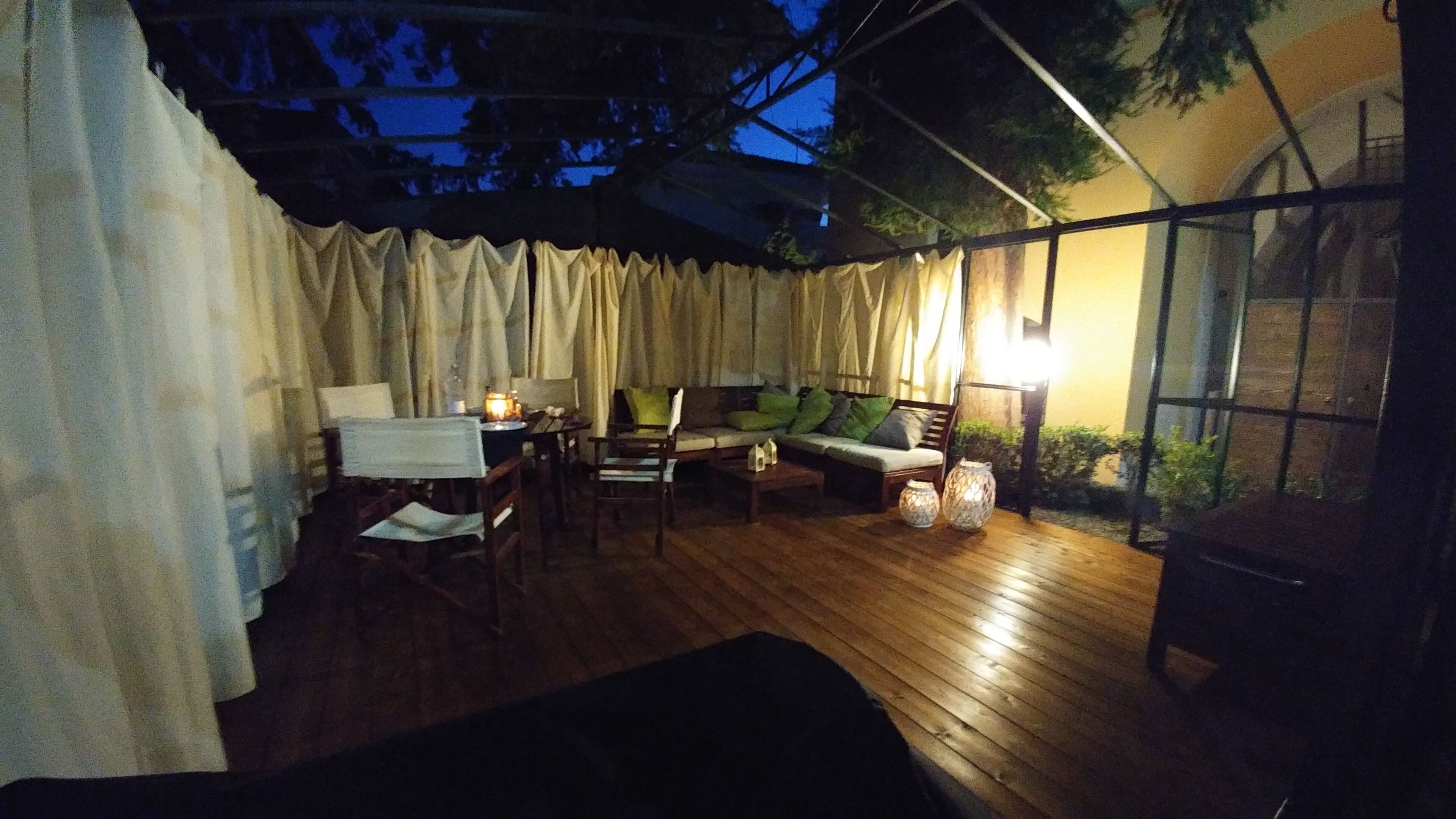 Un espace extérieur aménagé en terrasse, avec une plateforme en bois, un canapé, une table et des chaises.