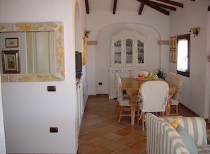 A dining area with a wooden table, striped chairs, and a white cabinet with glass doors. - Apartment With Sea View Terrace (La Maddalena)
