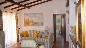 Ein Wohnzimmer mit gestreiften Sofas, einem Tisch und einem Gemälde, das eine Meereslandschaft zeigt.