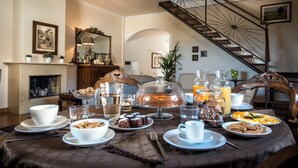 A dining table set with various breakfast items, a fireplace, and a staircase. - Residence Torremuzza - Charming House In The Heart Of Palermo With Lovely View (Palermo)