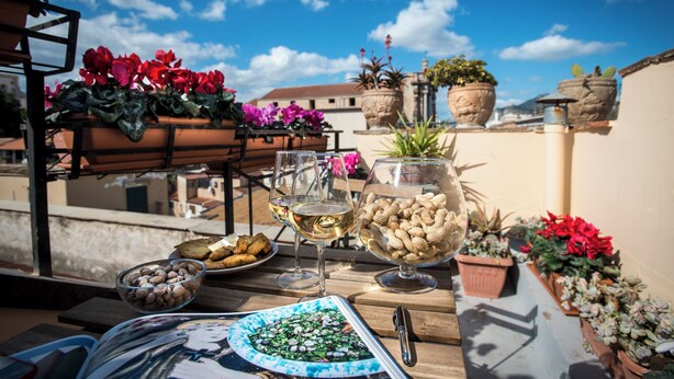 A terrace with a table set for a meal, potted plants, and a clear blue sky. - Residence Torremuzza - Charming House In The Heart Of Palermo With Lovely View (Palermo)