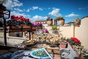 A terrace with a table set for a meal, potted plants, and a clear blue sky. - Residence Torremuzza - Charming House In The Heart Of Palermo With Lovely View (Palermo)