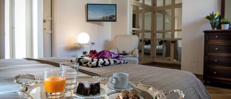 A neatly made breakfast tray with juice, coffee, and pastries on a bed.