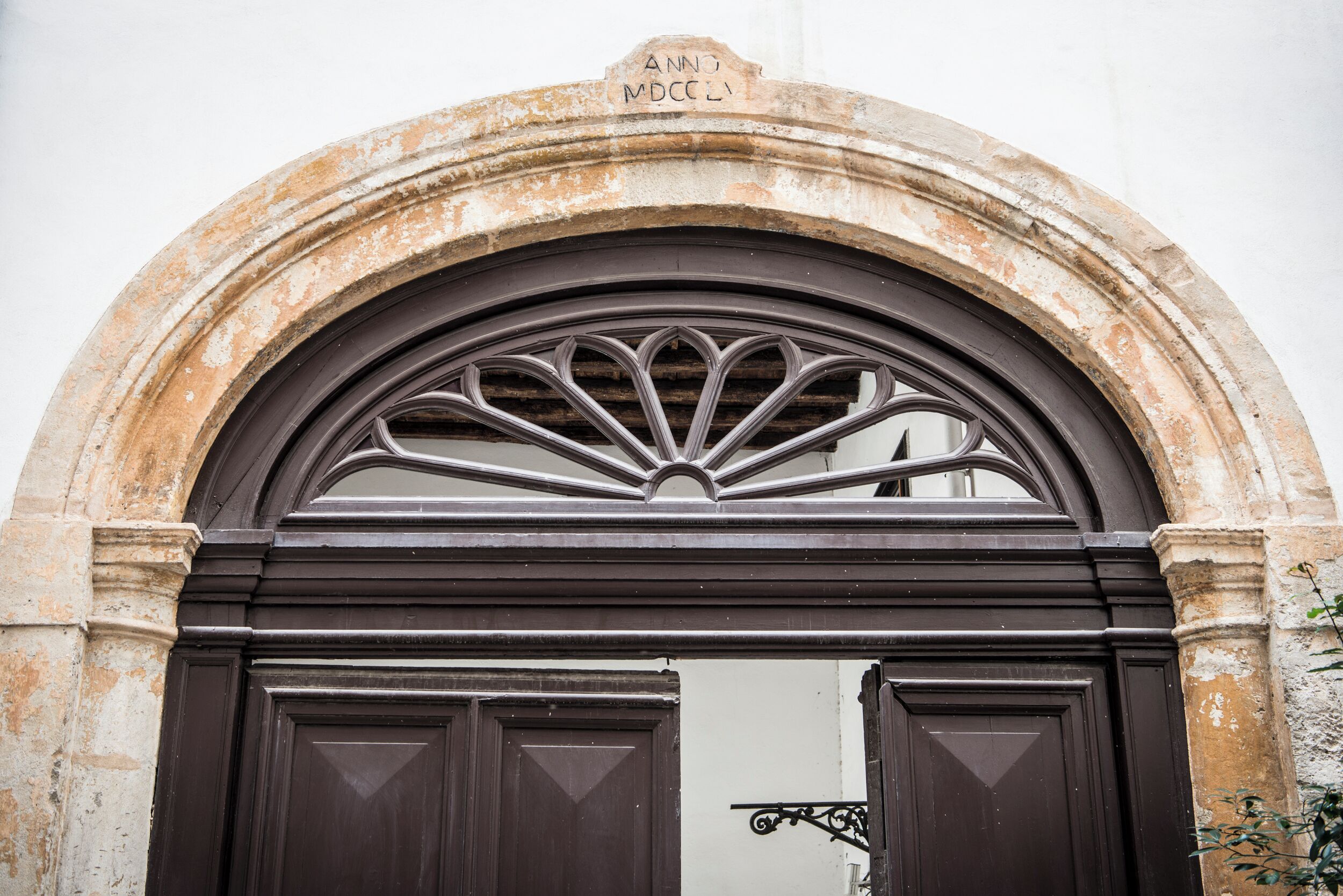 A stone archway with a decorative metal grille and a plaque above the door.