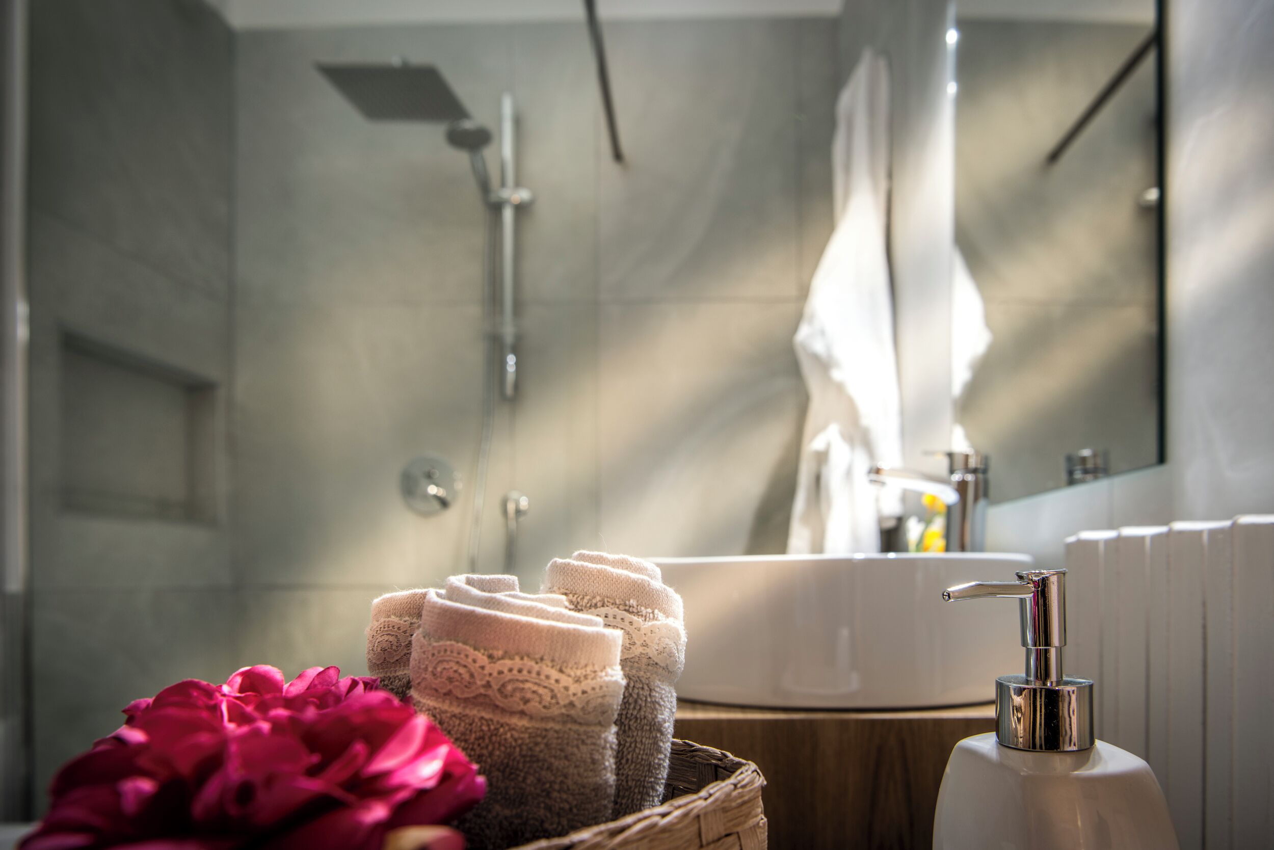 Een badkamer met een wastafel, douche en een zeepfles.
