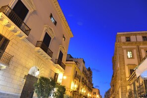 A street view at twilight with buildings featuring balconies and a street lamp.