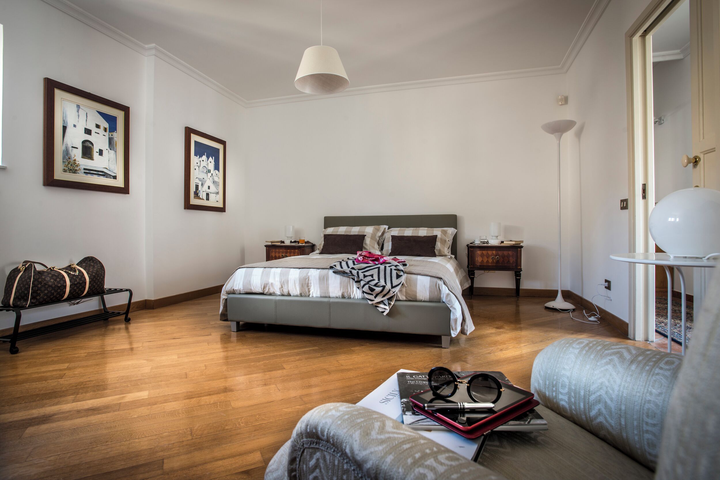 A bedroom with a bed, bedside tables, a lamp, and a sofa.