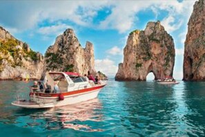 Un bateau sur une étendue d’eau calme, avec des falaises rocheuses en arrière-plan.