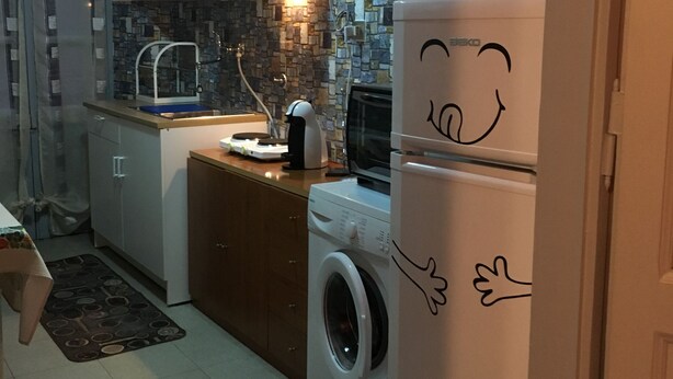 A compact kitchen with a washing machine, a refrigerator with a cartoon face, and a tiled backsplash. - Fronte Po Torino, Foot Of The Hill - Non-smoking Only (Turin)