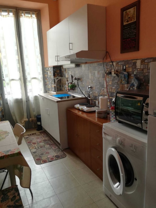 A compact kitchen with a washing machine, a microwave, and a sink.