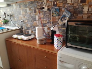 A kitchen with a stone backsplash, a microwave, a coffee maker, and a toaster on the counter.