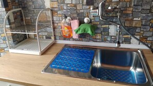A kitchen with a stone backsplash, a metal drying rack, a blue baking tray, and a stainless steel sink. - Fronte Po Torino, Foot Of The Hill - Non-smoking Only (Turin)