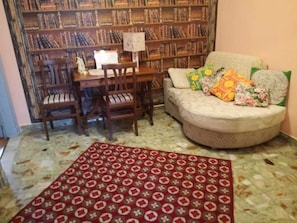 A cozy living room with a sofa, a coffee table, a bookshelf, and a patterned rug.
