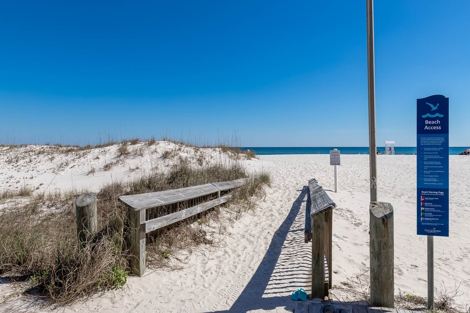 A wooden boardwalk leading to a beach with a sign indicating beach access.