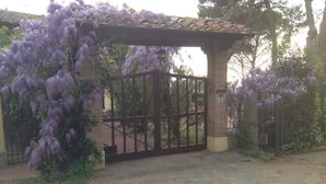 A gated entrance with a brick archway and a metal gate. - Villa Firenze Casa Serena (Montespertoli)