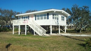 A white two-story house with a covered porch and a staircase leading to the upper floor.