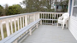 A wooden deck with a white railing and a white plastic chair.