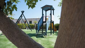 A playground with a climbing structure and slides, surrounded by a grassy area and trees. - Two Room Apartment Near the Beach 1 (Sciacca)