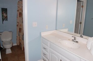 A bathroom with a toilet, sink, and mirror.