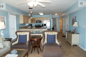 A spacious living room with a dining area, kitchen, and a hallway leading to another room.
