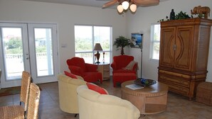 A living room with a red armchair, a beige sofa, and a wooden cabinet.